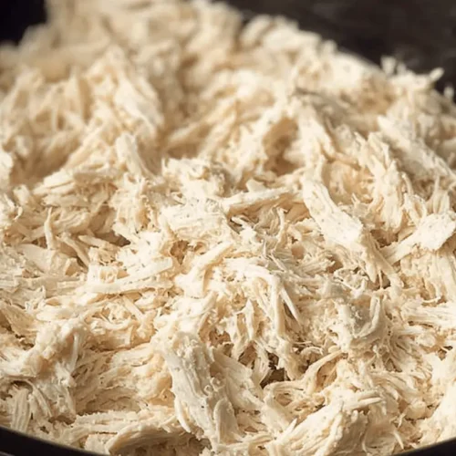 Easy Crockpot Shredded Chicken: Your Ultimate Meal Prep Solution 2 Close-up of a large quantity of tender crockpot shredded chicken in a dark bowl, ready for meals.