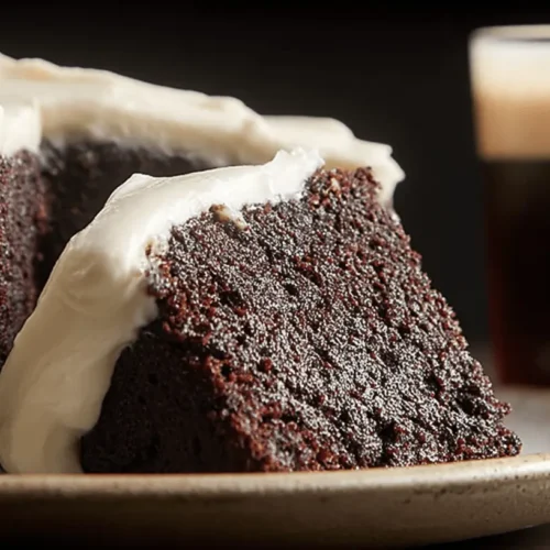 Rich & Moist Guinness Chocolate Cake with Cream Cheese Frosting 2 Moist slices of Guinness chocolate cake with creamy white frosting, served with a frothy stout.