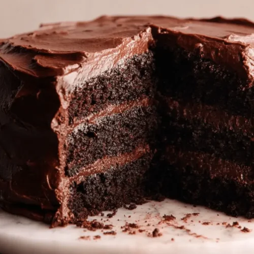 The Best Matilda Chocolate Cake Recipe: Rich, Moist & Fudgy Perfection 2 A decadent multi-layered matilda chocolate cake with a slice removed, revealing rich, moist interior and thick chocolate frosting on a marble stand.