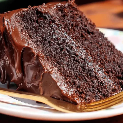 The Best Moist Chocolate Cake Recipe 2 A generously frosted slice of dark, moist chocolate cake on a decorative plate, highlighting a perfect moist chocolate cake recipe.