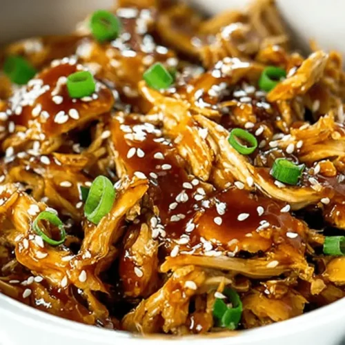Easy Slow Cooker Teriyaki Chicken 2 Close-up of succulent Slow Cooker teriyaki chicken, garnished with sesame seeds and green onions in a ceramic bowl.
