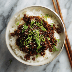 Bowl of Korean ground beef served over white rice with green onions.