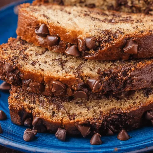 The Best Moist Chocolate Chip Banana Bread Recipe 2 Close-up of moist, stacked slices of chocolate chip banana bread on a blue ceramic plate.