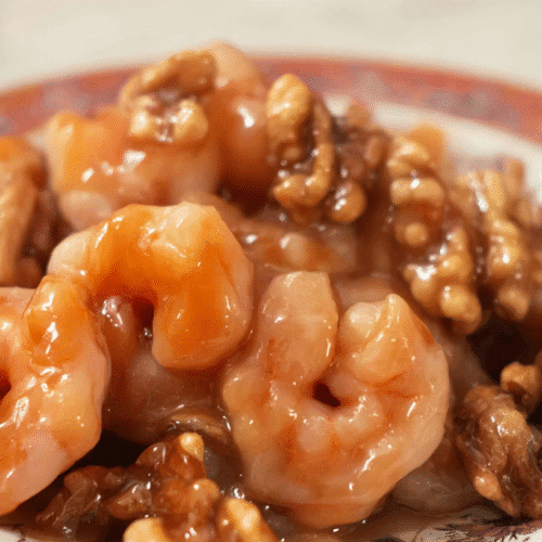 simple Honey Walnut Shrimp taken with an old camera, close-up, high-angle, glossy amber sauce, plump shrimp, crunchy walnuts, decorative Chinese plate, intricate patterns, soft studio lighting, shallow depth of field.