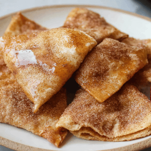 simple air fryer cinnamon sugar tortilla taken with an old camera, golden-brown crispy pastry, cinnamon sugar, glistening glaze, fresh red strawberry, neutral ceramic plate, light countertop, soft natural light.