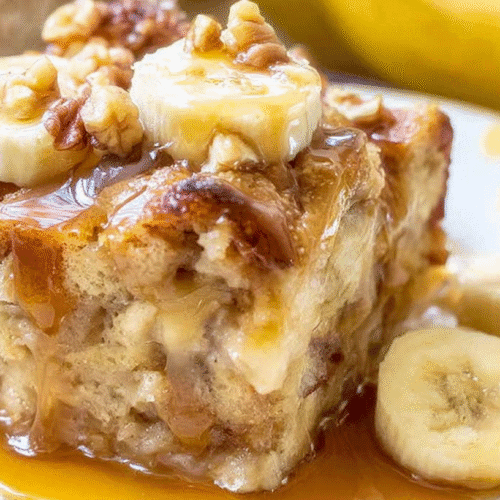 simple banana bread pudding taken with an old camera, delicious slice, warm moist texture, rustic shape, visible bread chunks, creamy custard, chopped nuts, golden caramelized crust, fresh banana slices, glossy amber caramel sauce, white plate with yellow dots, blurred ripe bananas, warm golden background, soft natural light.