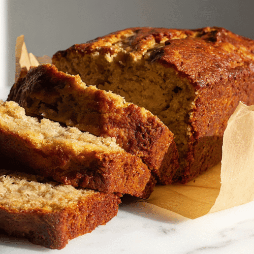 Ultimate Brown Butter Banana Bread Recipe 4 simple brown butter banana bread taken with an old camera, freshly baked, golden-brown crust, moist crumb, partially sliced, crumpled parchment, white marble, dramatic lighting, sharp shadows, minimalist aesthetic.