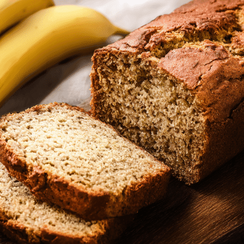 simple protein banana bread taken with an old camera, golden-brown banana bread loaf, sliced, moist interior, ripe bananas, rustic wooden cutting board, well-lit, fresh atmosphere.