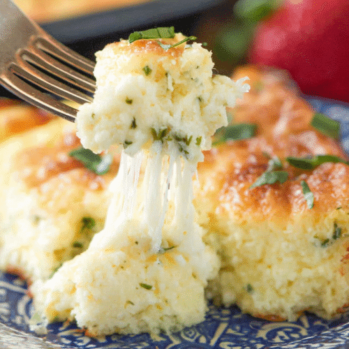 Easy Cheesy Egg Casserole: The Ultimate Bread-Free Brunch Recipe 6 simple cheesy egg casserole taken with an old camera, close-up, cheesy baked gratin, fork lifting, dramatic cheese pull, golden brown crust, fresh green herbs, soft creamy texture, blue and white ceramic plate, intricate floral pattern, fresh red strawberries, soft natural light, bokeh background.