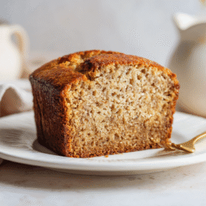 Golden banana bread made without eggs, sliced on a white platter with soft moist texture.